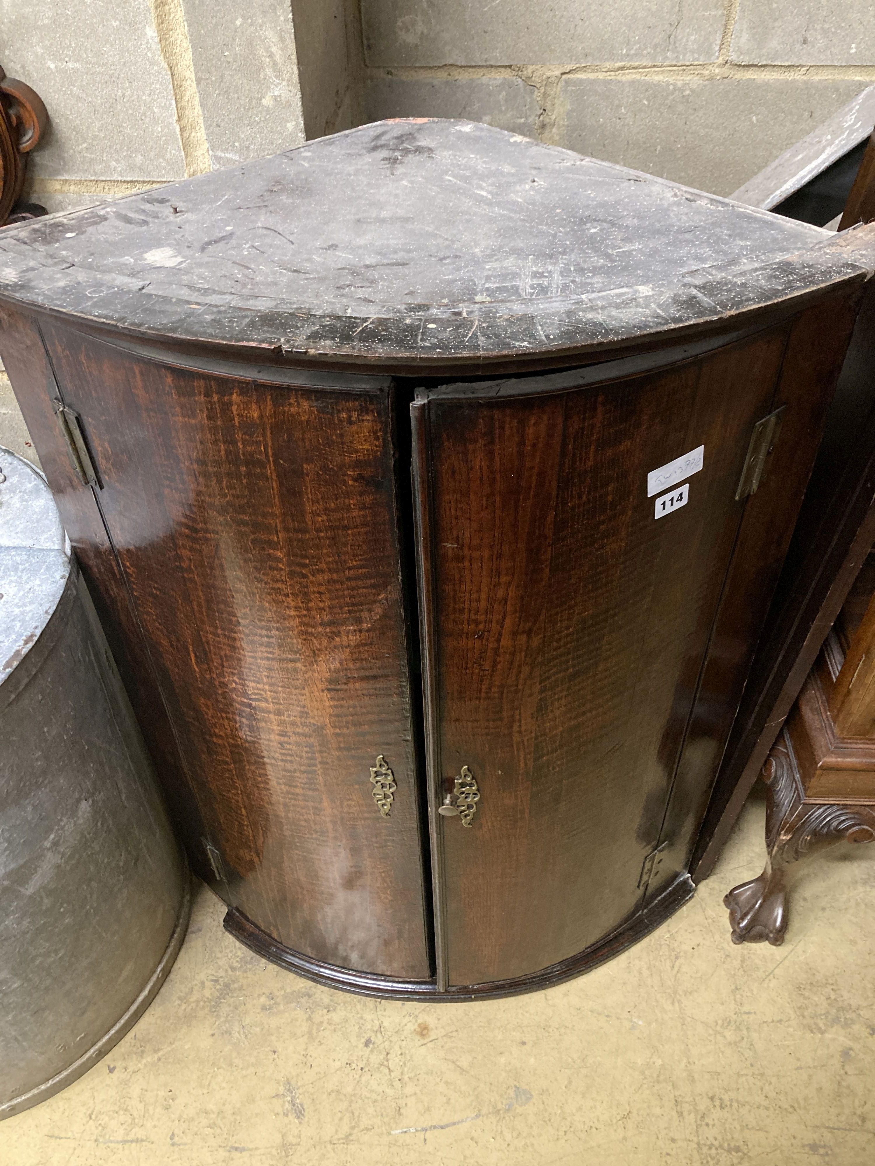 A George III oak bow-fronted hanging corner cupboard, width 77cm, depth 49cm, height 100cm